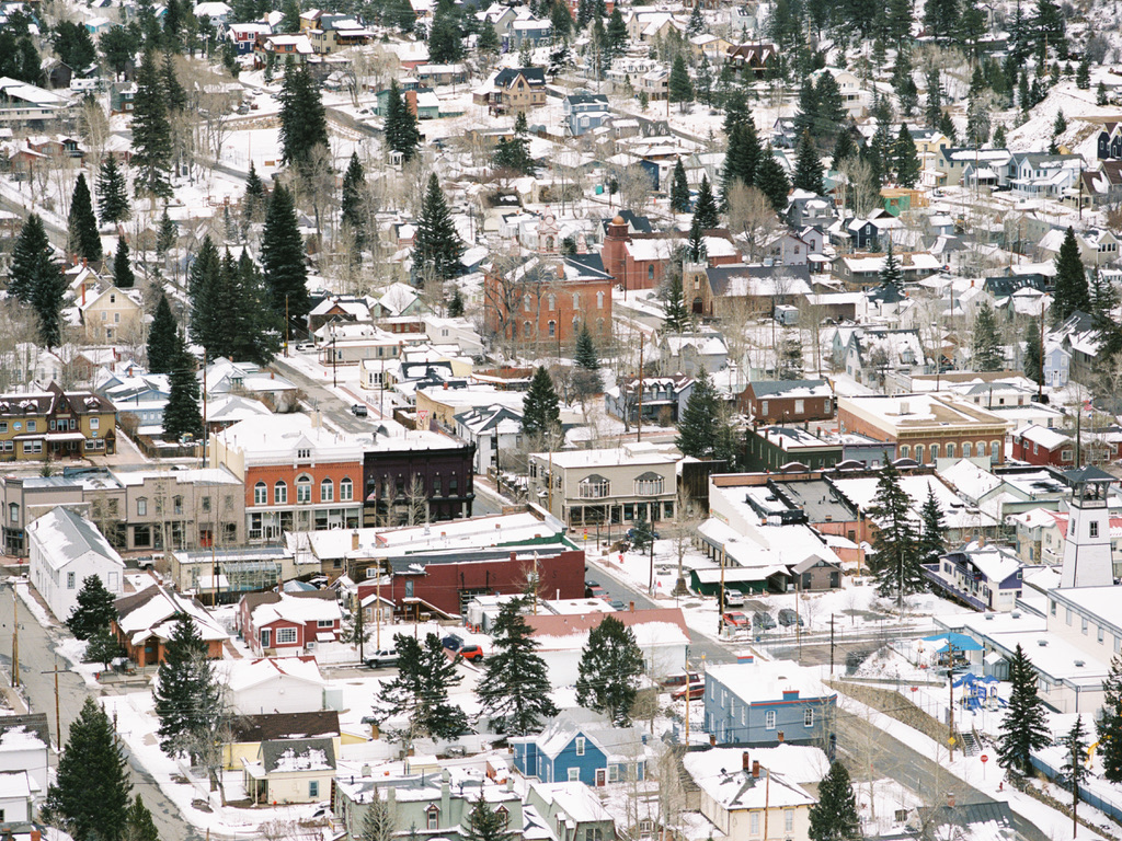 Aerial view of a small town blanketed in snow. The town, much like the meticulously crafted projects by Millworks Web Design & Graphics, features a mix of residential houses, commercial buildings, and a few scattered trees. The roofs and streets are covered with snow, creating a serene winter landscape.