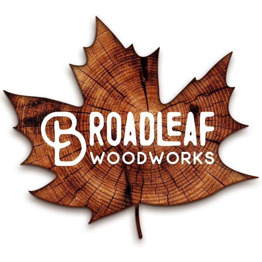 A logo for Broadleaf Woodworks featuring a detailed, textured wooden leaf cutout with prominent grain patterns. The company name "Broadleaf Woodworks" is displayed in bold, white letters across the center of the leaf, showcasing their expertise in graphic design and digital marketing.