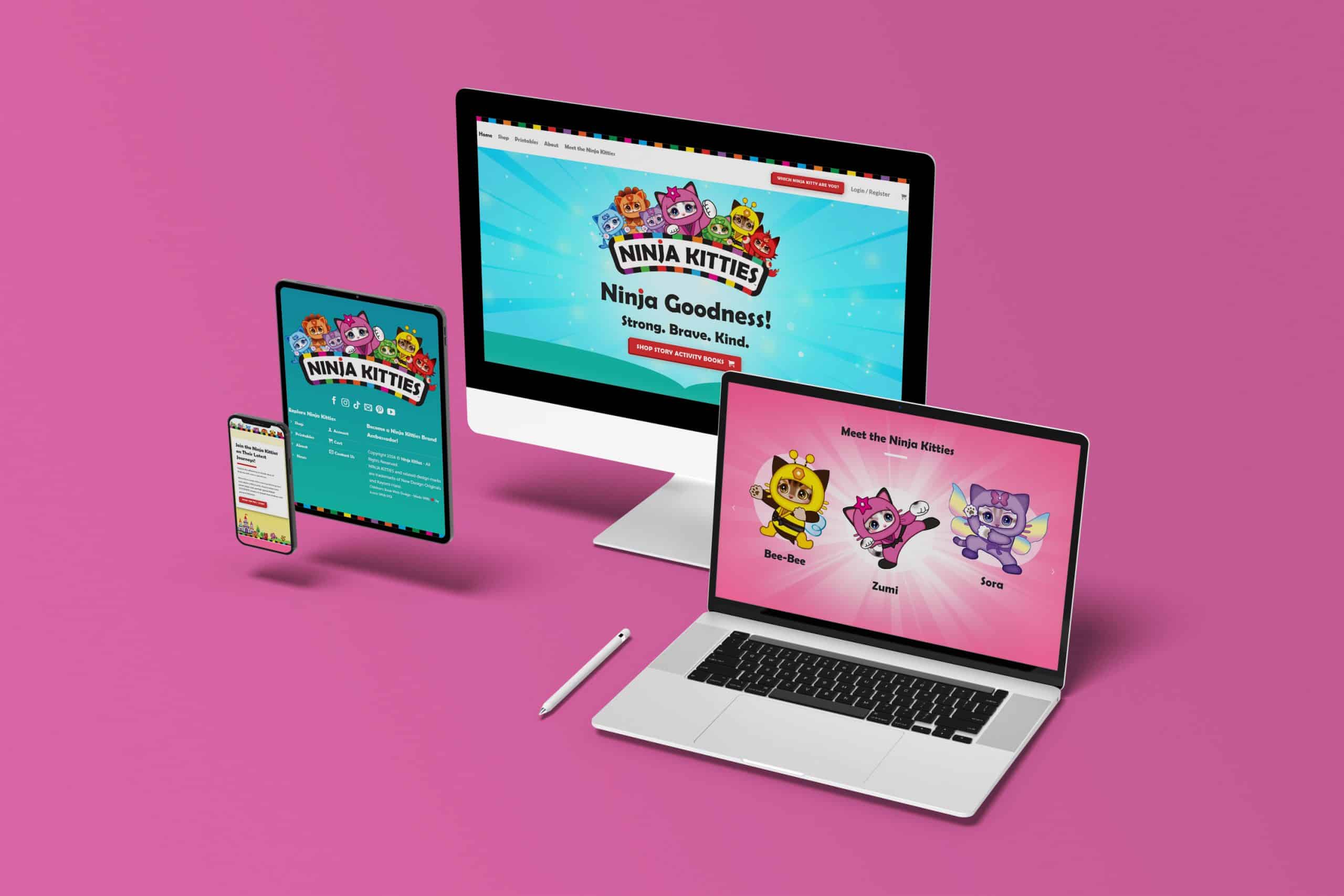 A workspace featuring a smartphone, tablet, desktop monitor, and laptop displaying the "Ninja Kitties" custom website against a pink background. The site showcases colorful cartoon kitties with text that reads "Ninja Goodness! Strong, Brave, Kind," demonstrating expert graphic design and digital marketing.