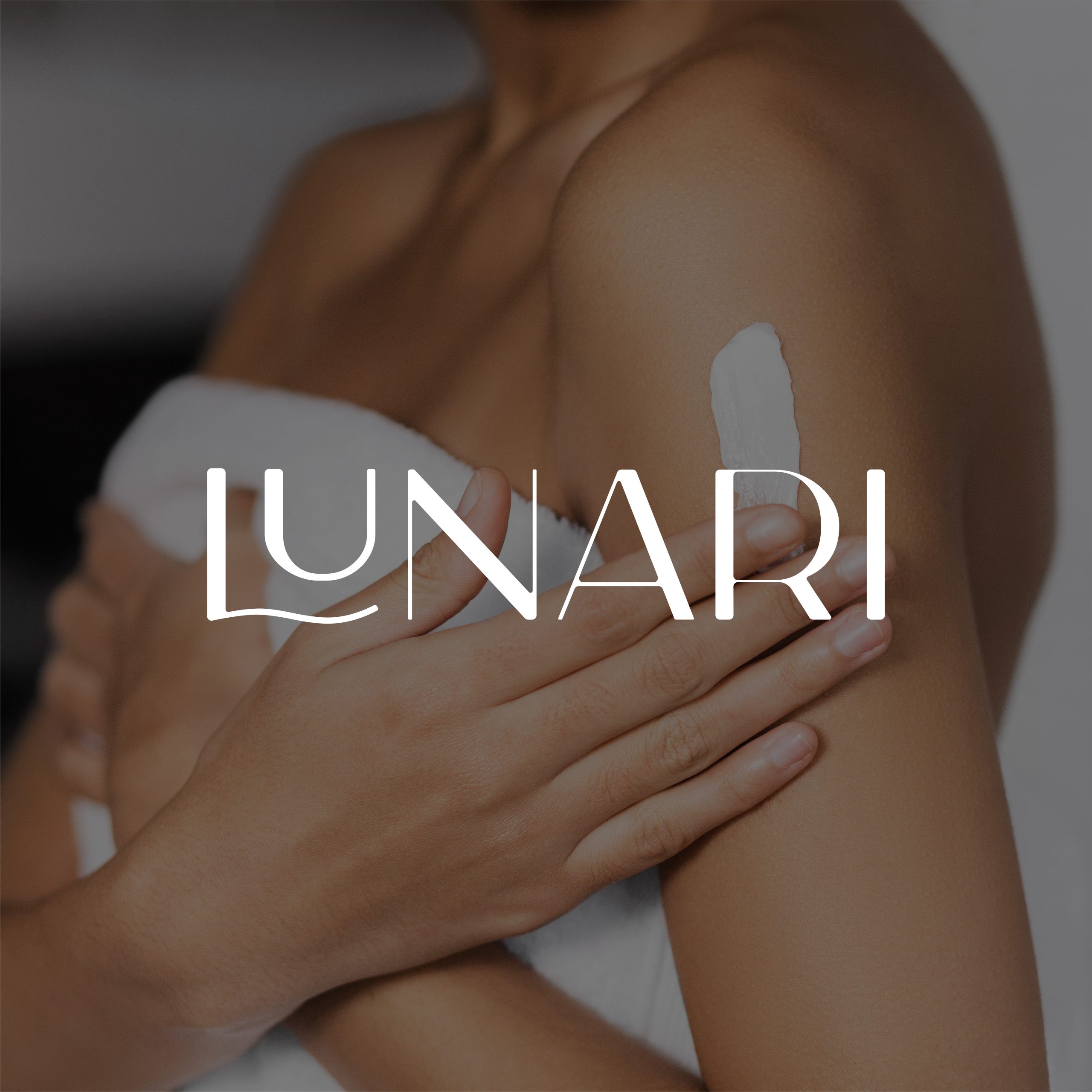 A person in a towel applies lotion to their shoulder, radiating self-care. The word LUNARI is displayed in large white letters across the image.